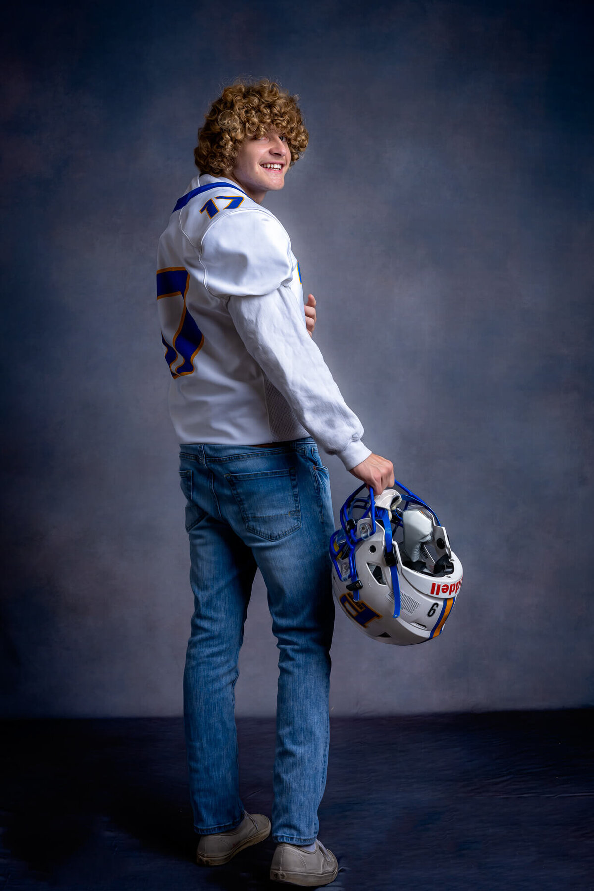 Prescott Badgers football player walks with helmet in Prescott senior photos
