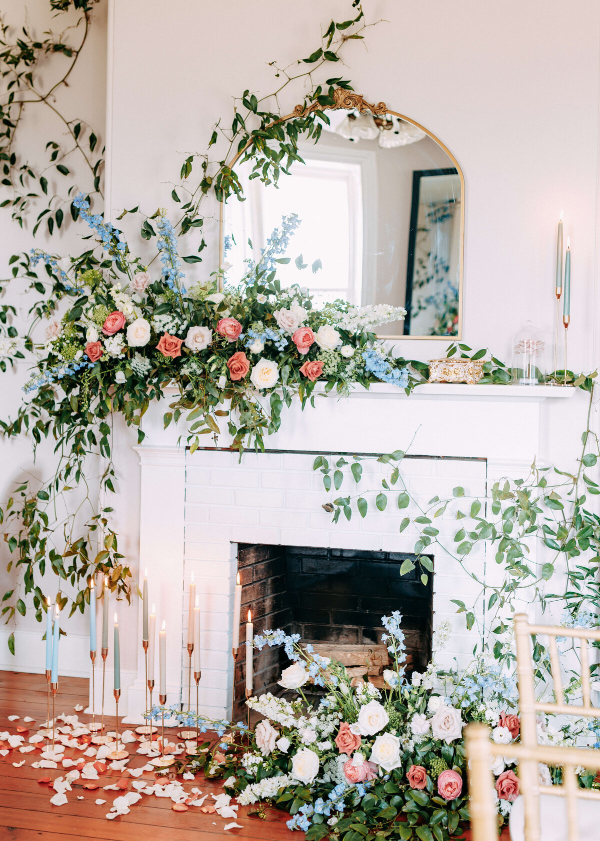 fireplace decorated with large floral displays of blue, peach and ivory blooms