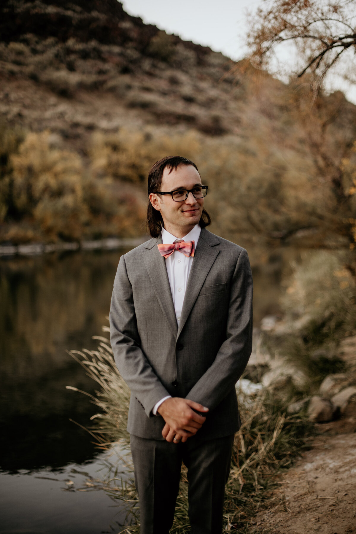 groom looking off in front of a river
