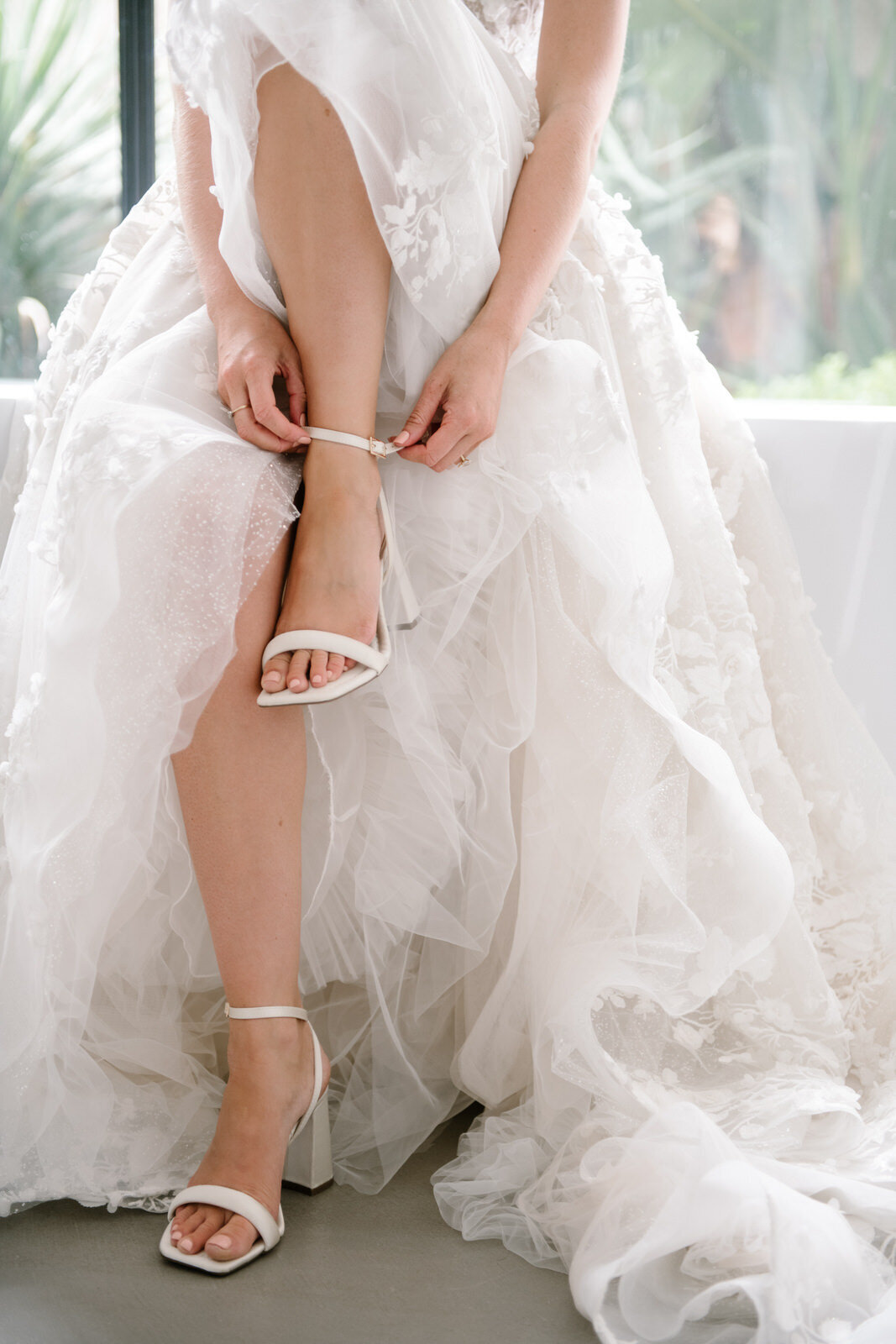 bride putting on wedding shoes in her berta dress at villa serena