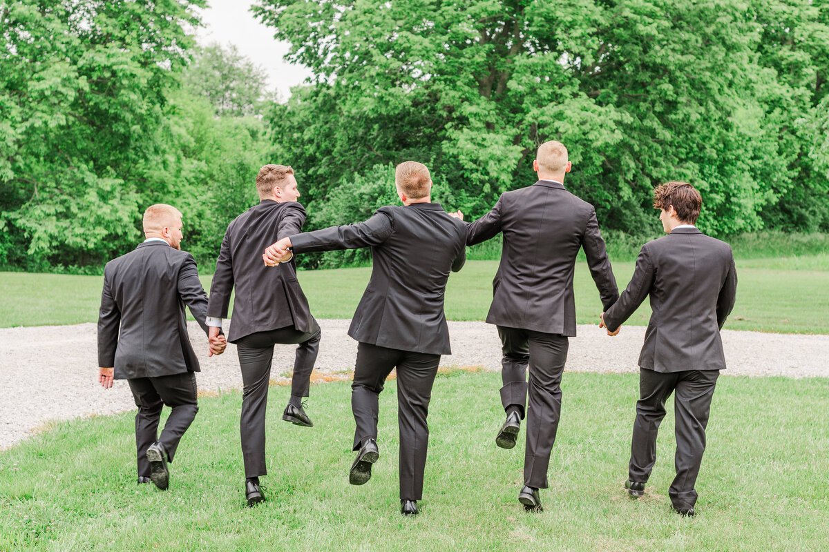 Groom with his groomsmen skipping with joy at the Farmstead in Harrodsburg