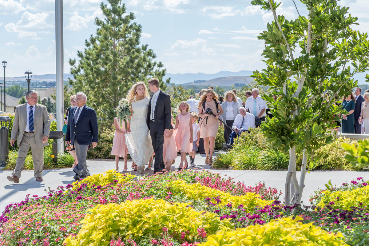 a bride and groom walking with a group of people on their wedding day