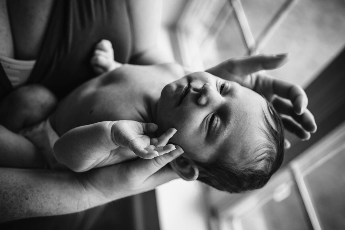 Black and white newborn picture stretching near a window Newborn Portrait Photography