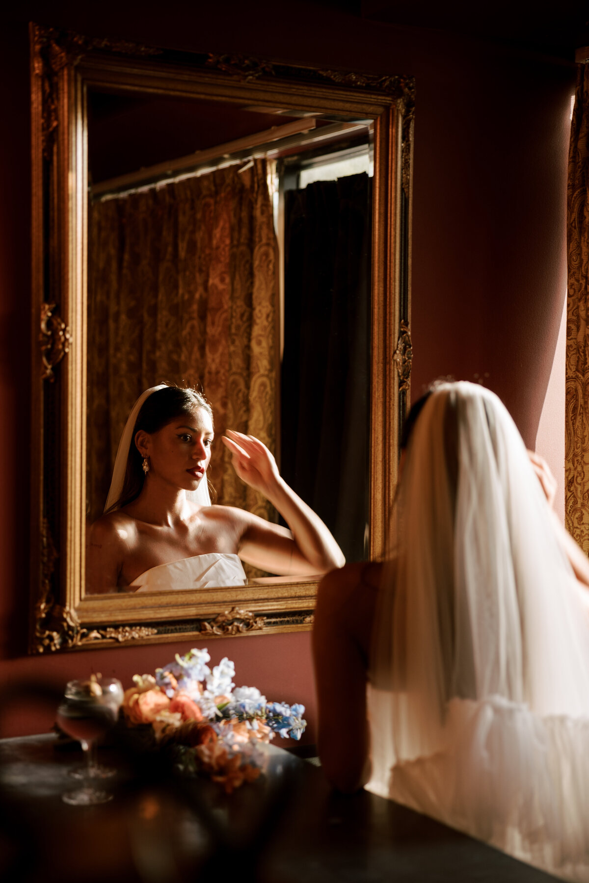 Bride captured in a quiet moment looking into the mirror while getting ready in Carmel, California — shot on 35mm film by Kate Winters Photography.