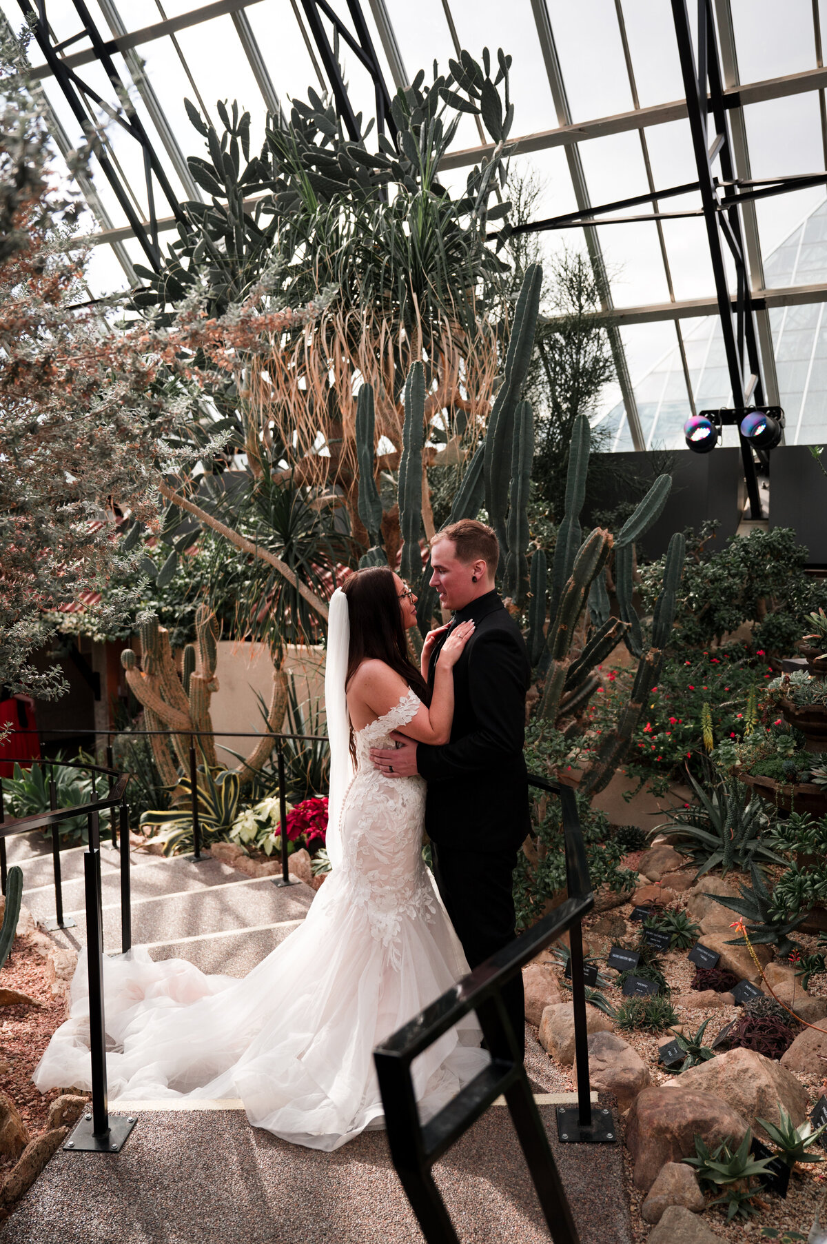 bride and groom stand facing each other in a pyramid greenhouse at the muttart conservatory in Edmonton, Alberta