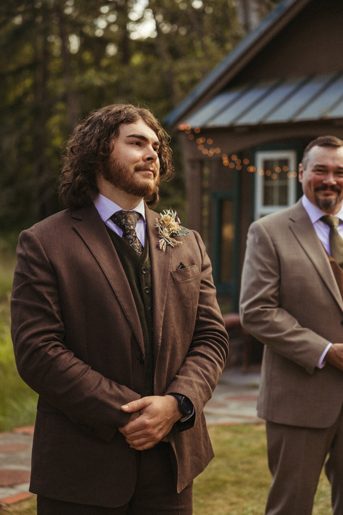 An emotional groom tears up as his bride walks down the aisle to him during an outdoor wedding ceremony.