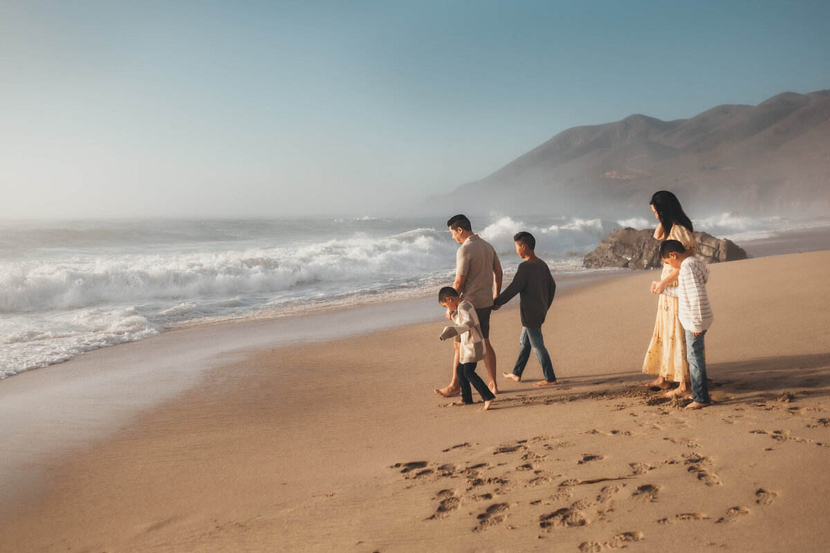 Family of five walking along Garrapata Beach in Big Sur at sunset