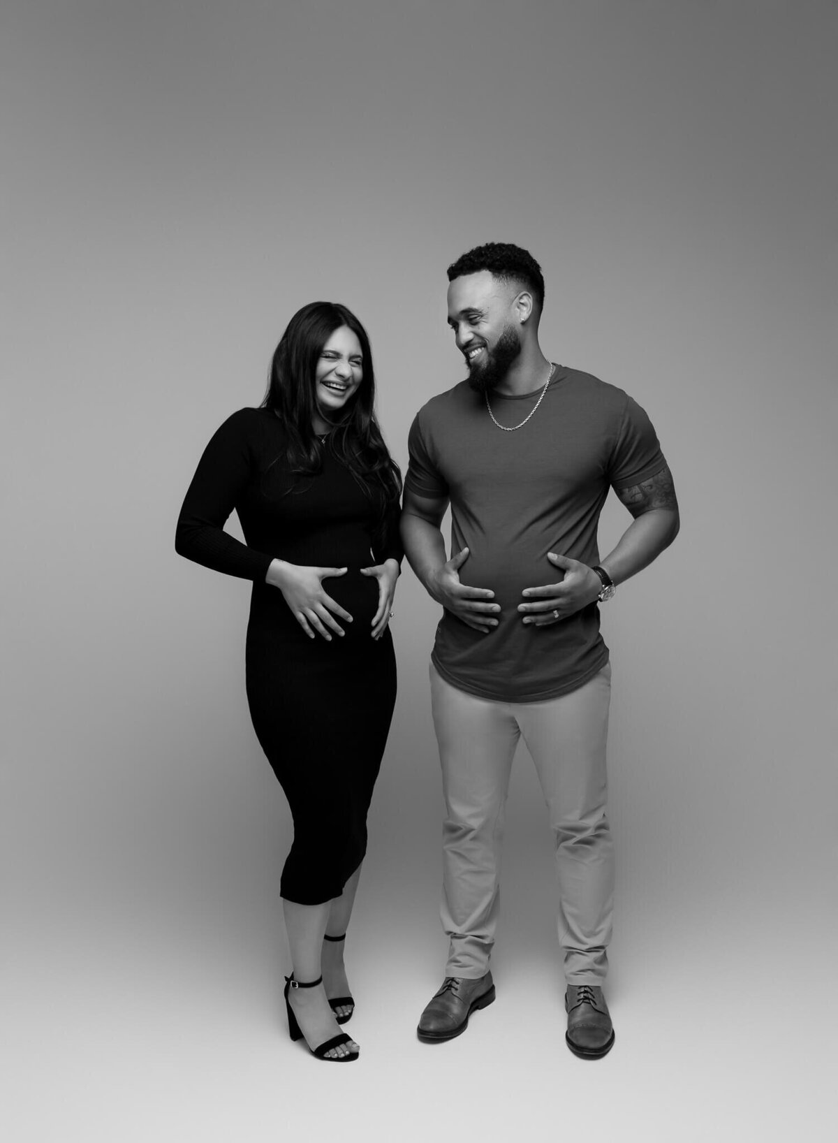 couple holding their bellies to announce their pregnancy
