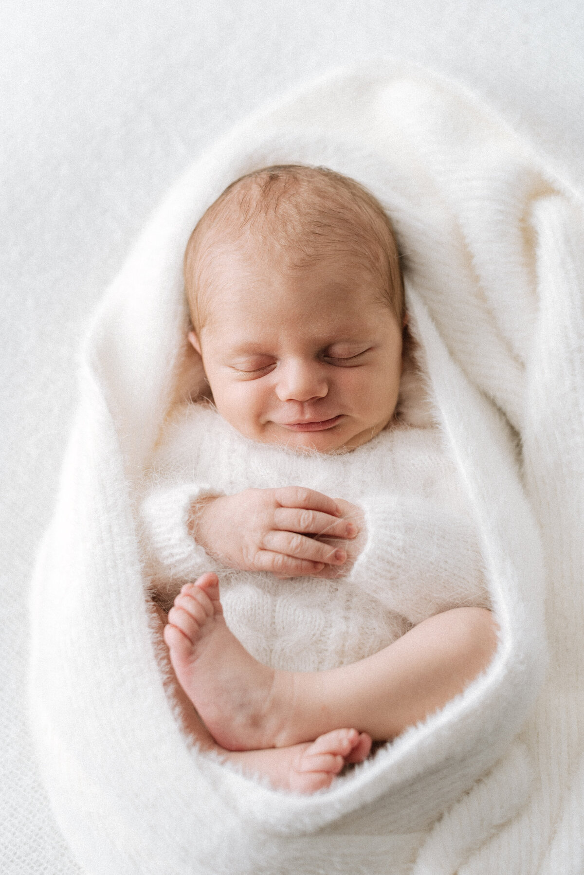 Newborn baby girl sleeping in a blanket in Billingshurst newborn photoshoot