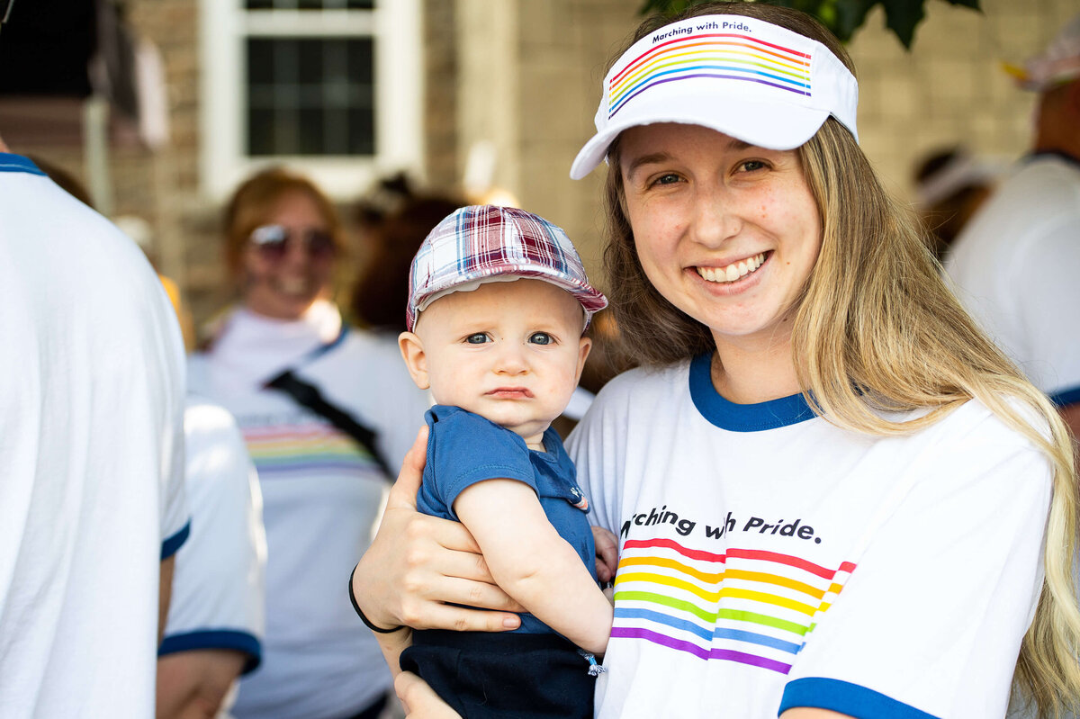 A mom and her baby wearing pride t-shirts and visors during the Tweed Canopy Growth Pride Parade.  Captured by JEMMAN Photography COMMERCIAL