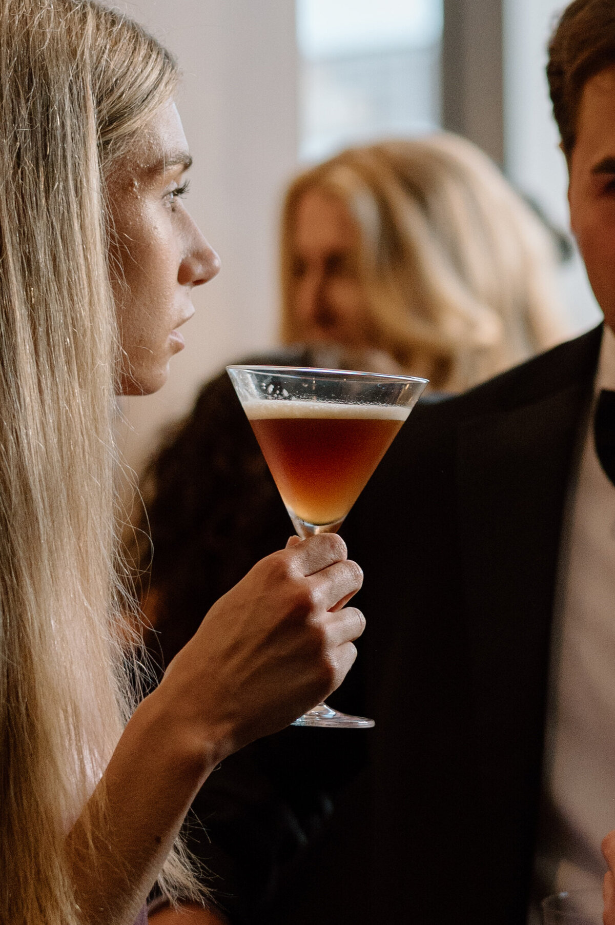 Wedding guest raising a cocktail glass, toasting during the Toronto reception.