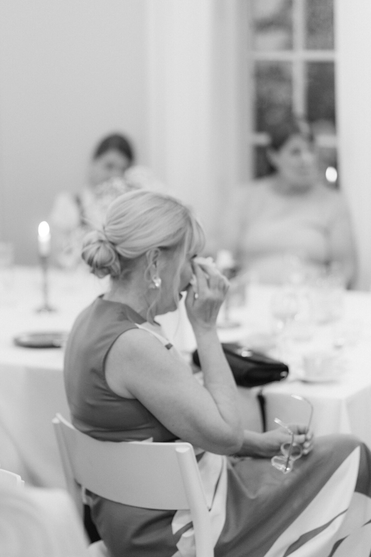Documentary wedding photograph of a wedding guest listening to a speech to bride and groom in Airisniemi manor in Turku, Finland. Atmosphere captured by wedding photographer Hannika Gabrielsson.