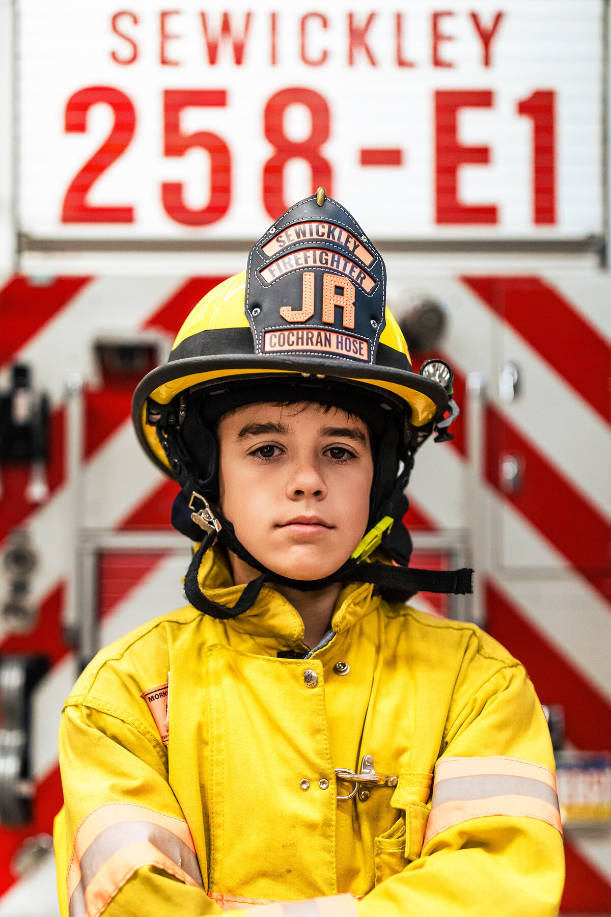 A 12 year-old boy wears a junior firefighting outfit in the Sewickley fire house during a family photography session.