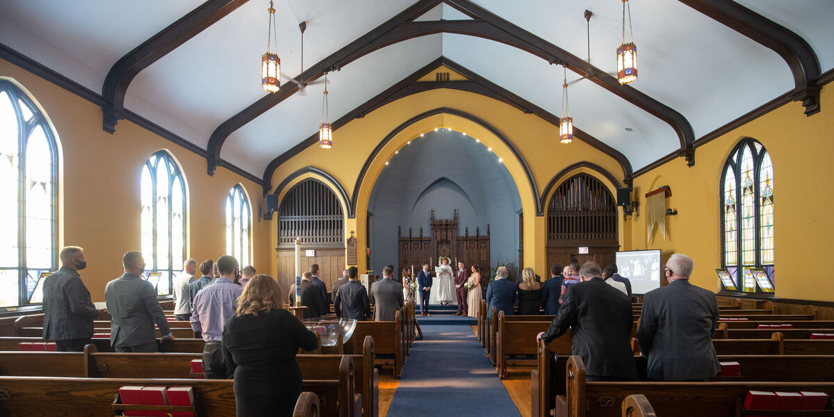 A group of people are sitting in a church watching a wedding ceremony