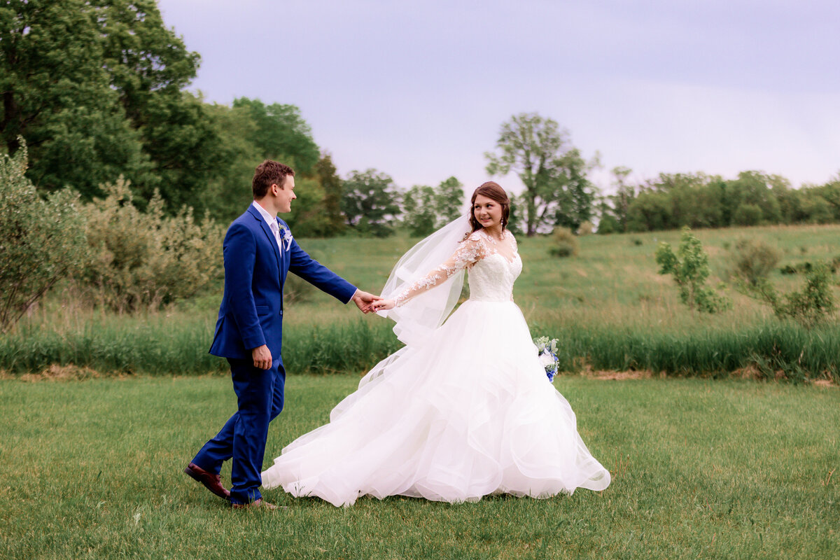 A bride leads her groom through a field in Chicago.