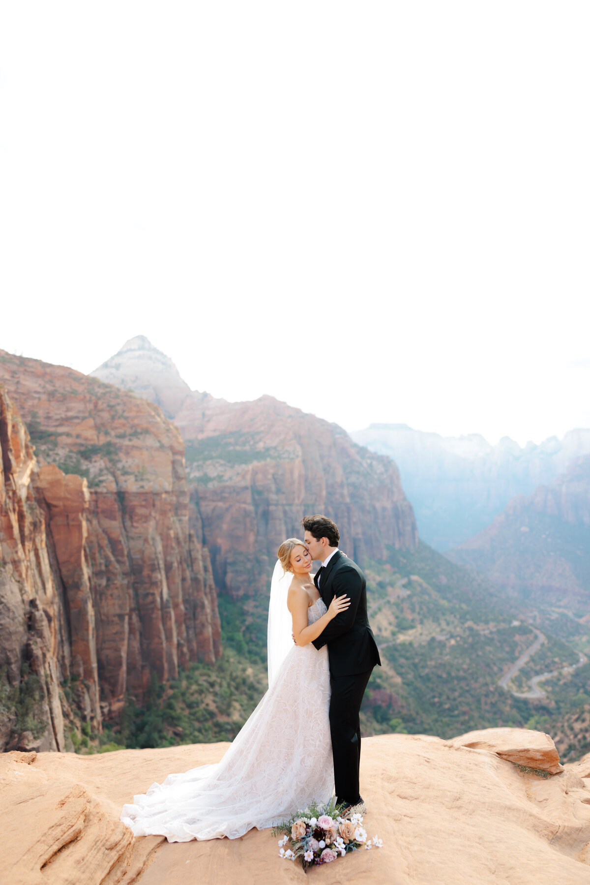 a bride and groom eloping on a cliff at zion national park