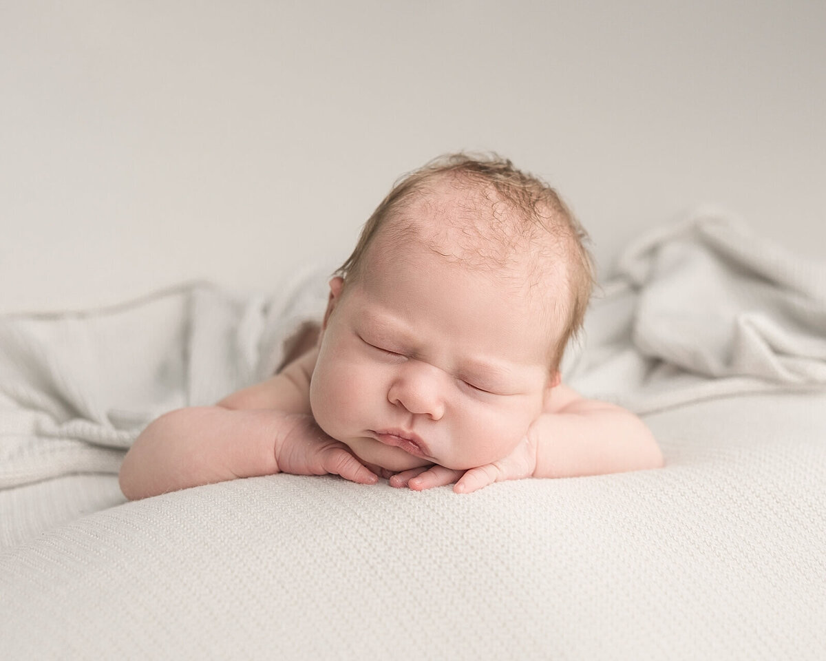 baby boy with head on hands sleeping in newborn pictures