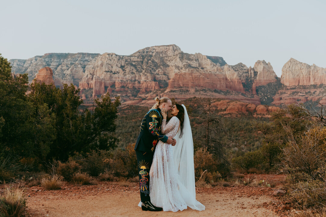 wedding couple standing kissing in front of red rocks in sedona arizona