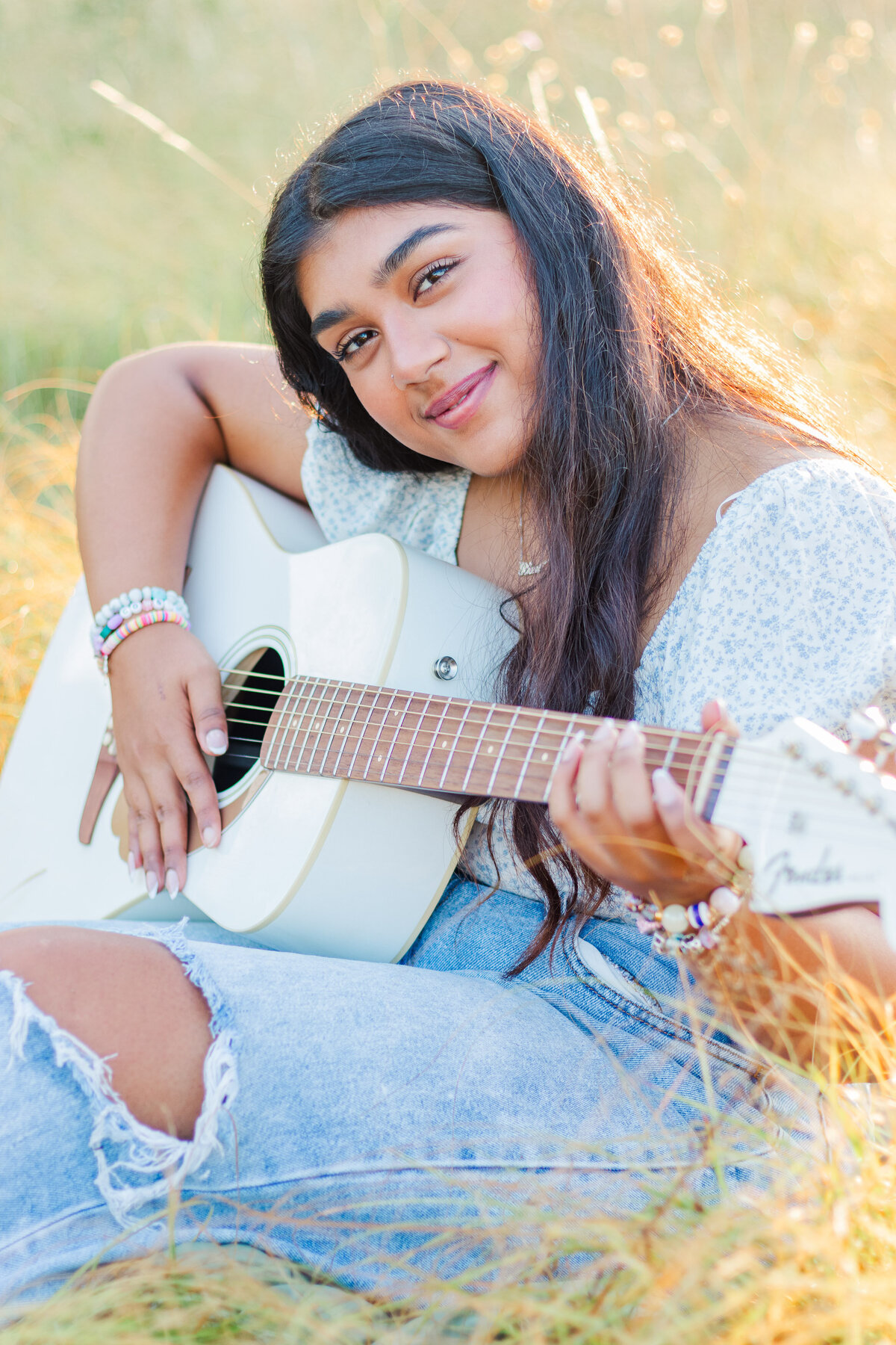 girl sitting in a field with her guitar