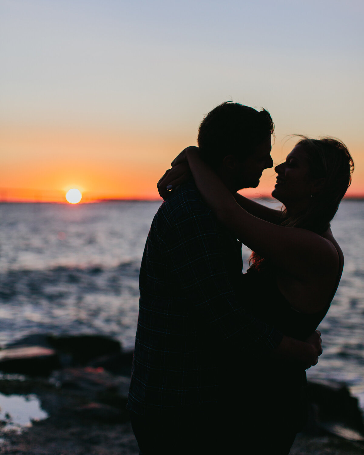 The silhouette of a couple about to kiss at the beach at sunset 