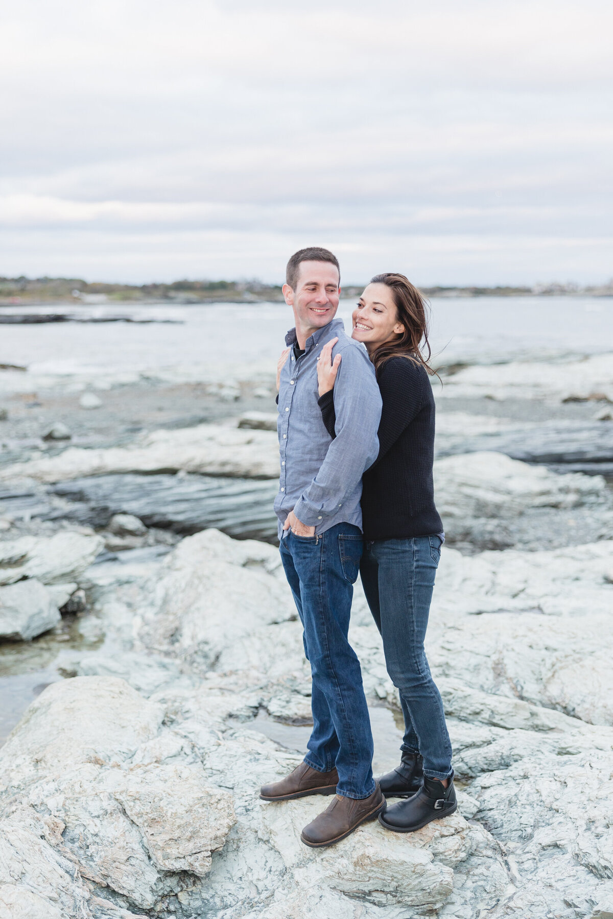 A bride to be hugs her fiancee from behind at Brenton Point Park in Newport RI