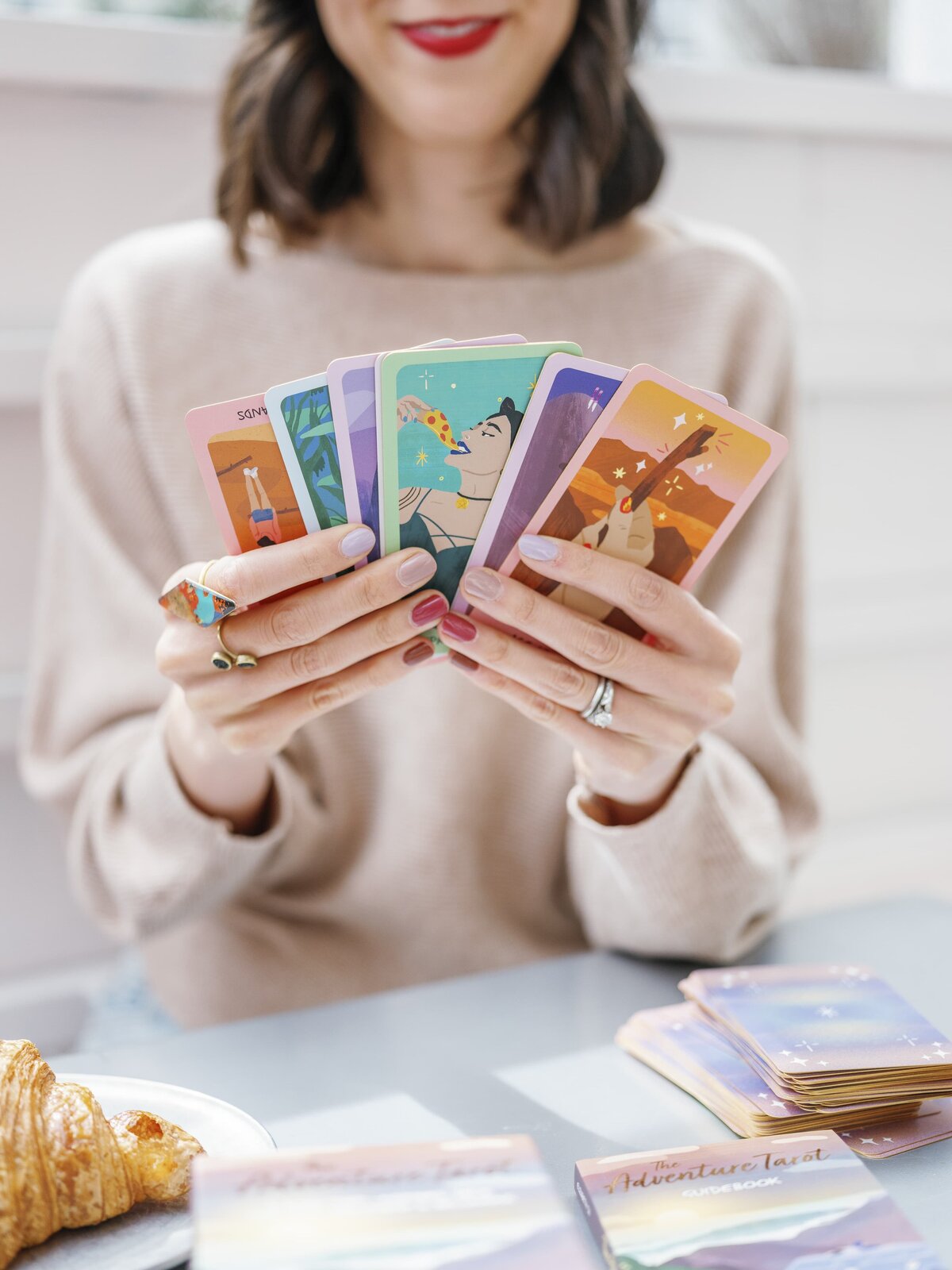 Close-up of woman holding colorful tarot cards at café table during NYC brand photography session.
