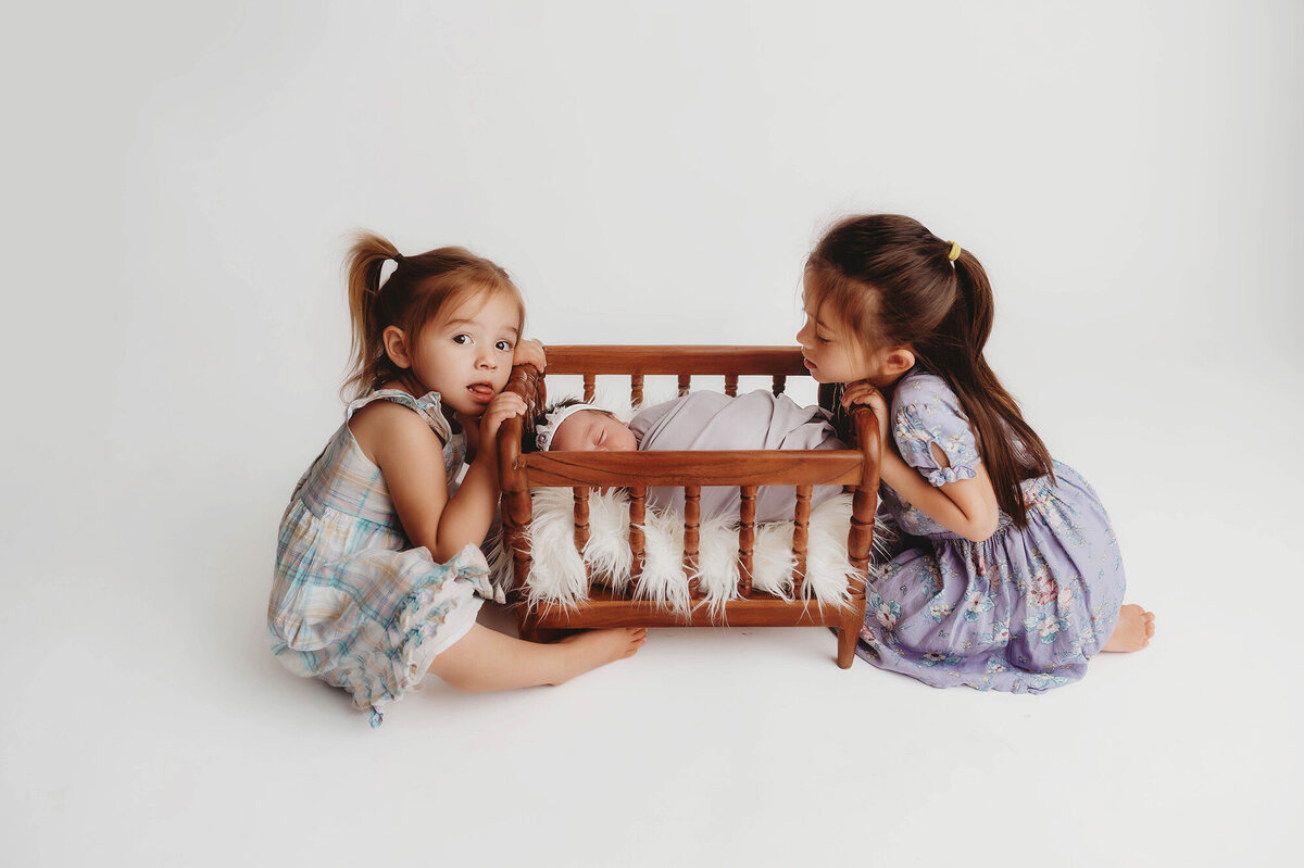 Siblings embrace their baby sister during Newborn Photoshoot in Charleston, SC.