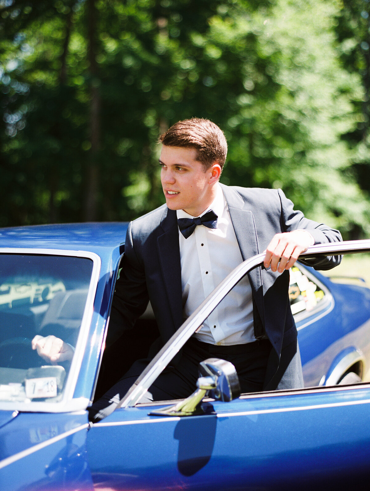 Groom stepping out of a blue car