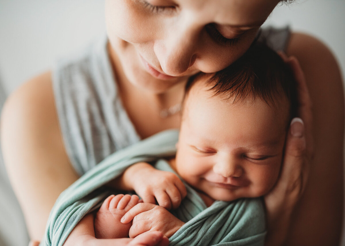 Aubin Grove, Perth newborn  photographer session in studio - newborn baby in mum's arms caught in a smiling moment