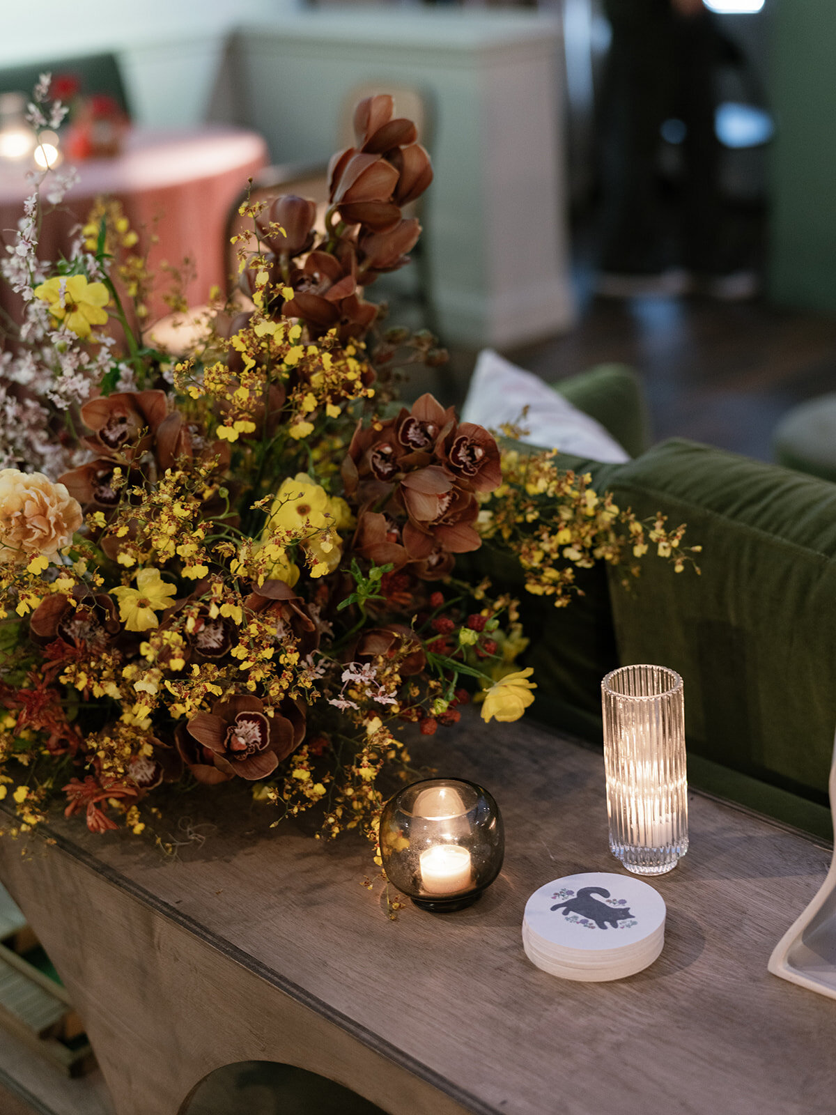 Trailing bar meadows with florals in hues of purple, ruby, copper, gold, and rust for fall wedding reception. Sculptural product clustered floral design for fall wedding. Product clustered floral statements in a tasteful fall color palette of copper, ruby, gold, burgundy, rust, and lavender. Orchids, bittersweet berries, butterfly ranunculus, and tulips are highlighted. Unique floral design with flower forward large scale installations. Design by Rosemary & Finch Floral Design in Nashville, TN.