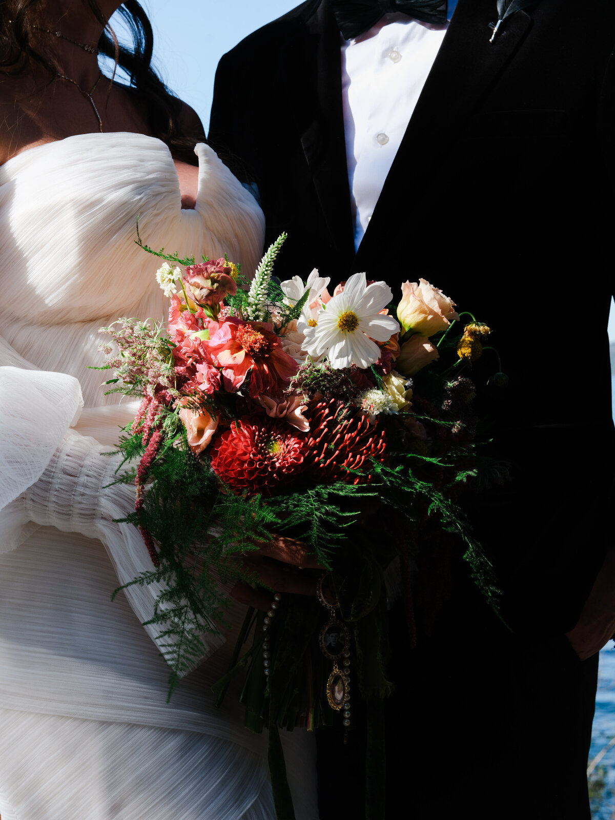 Bride and groom holding colorful bouquet of florals