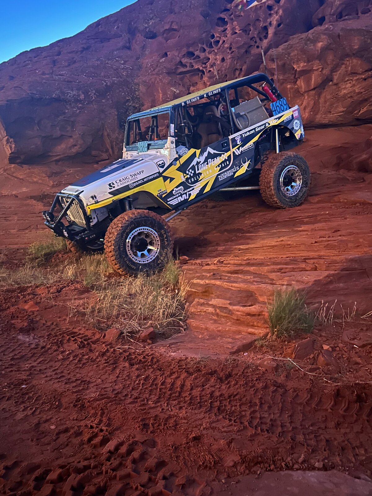 jeep driving over large red rocks