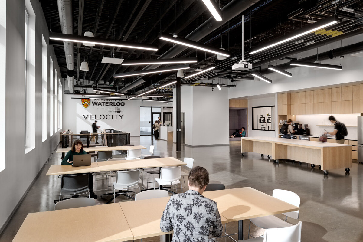 Interior architecture of the Velocity Innovation Arena cafeteria with entrepreneurs working in the communal space in Kitchener Waterloo, Ontario. Photograph by Brandon Marsh Photo & Video Productions for Diamond Schmitt Architects, Velocity, Smith + Andersen, and Melloul Blamey Construction.