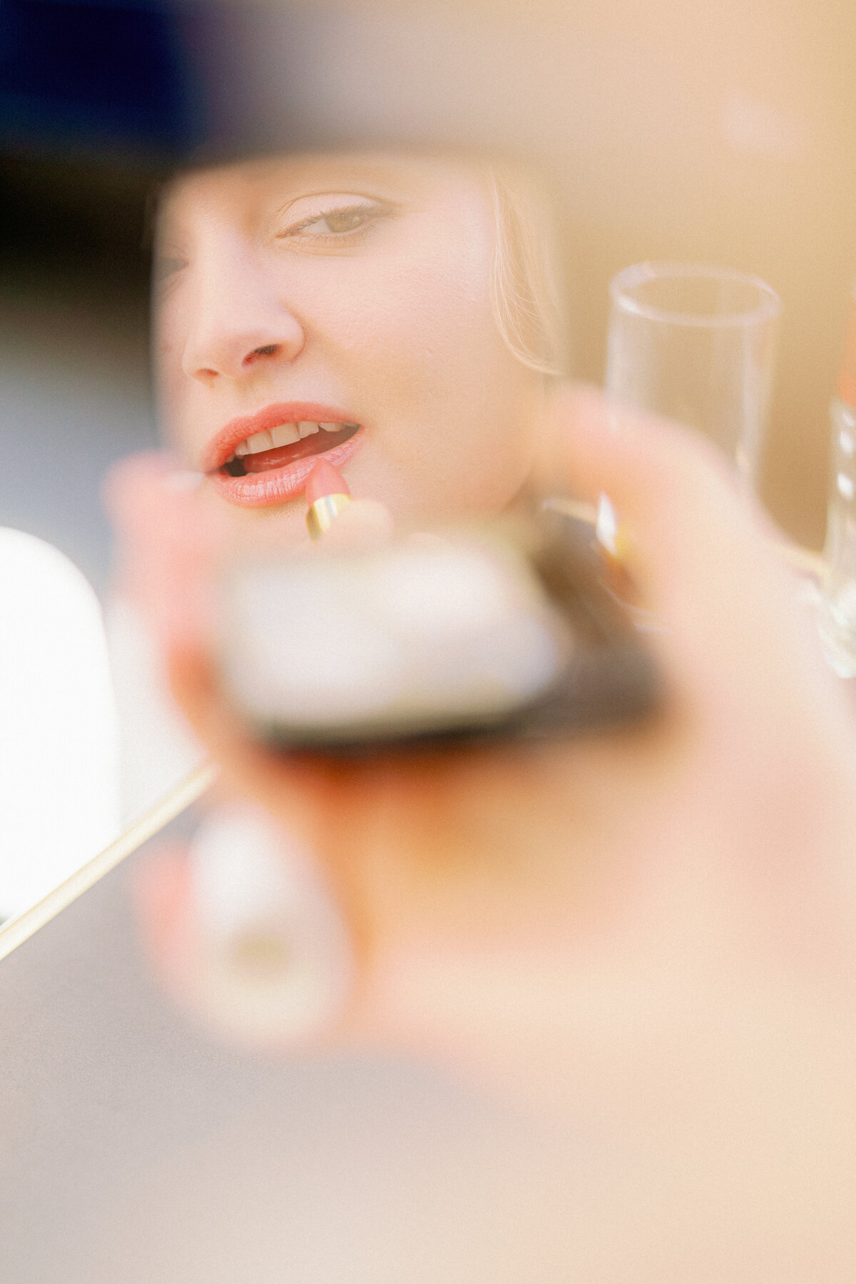 a woman putting lipstick on with a reflection of her in a mirror