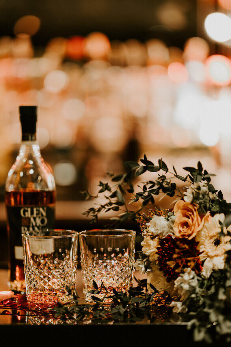 Bar avec une bouteille d'alcool, un bouquet et deux verres. Style vintage. Shooting photo mariage.