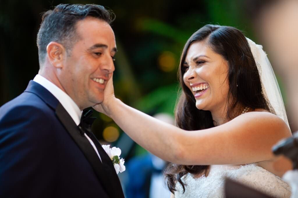 A bride wiping a tear from a groom's face