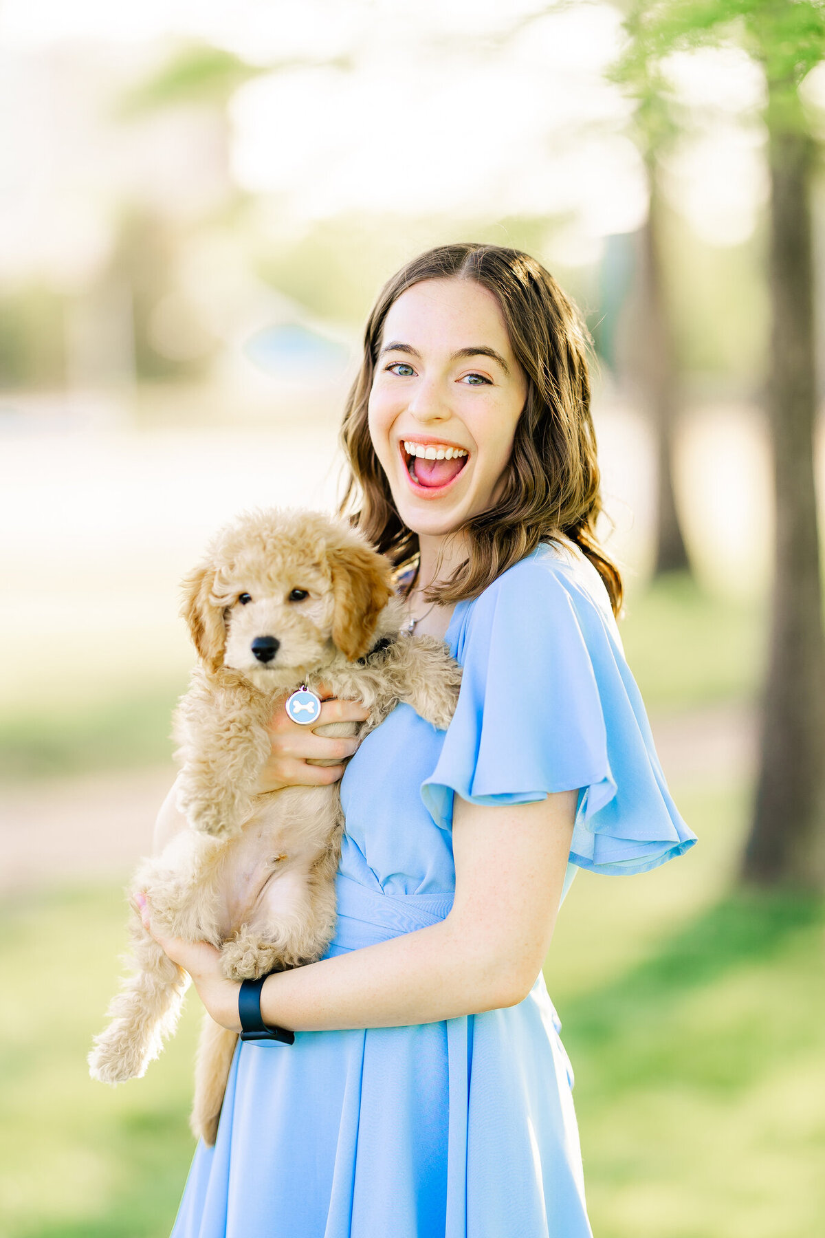 sweet girl smiling big with little dog in arms