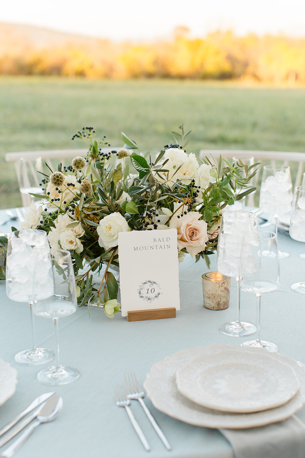 Wedding reception table with floral centerpiece and custom table number calligraphy