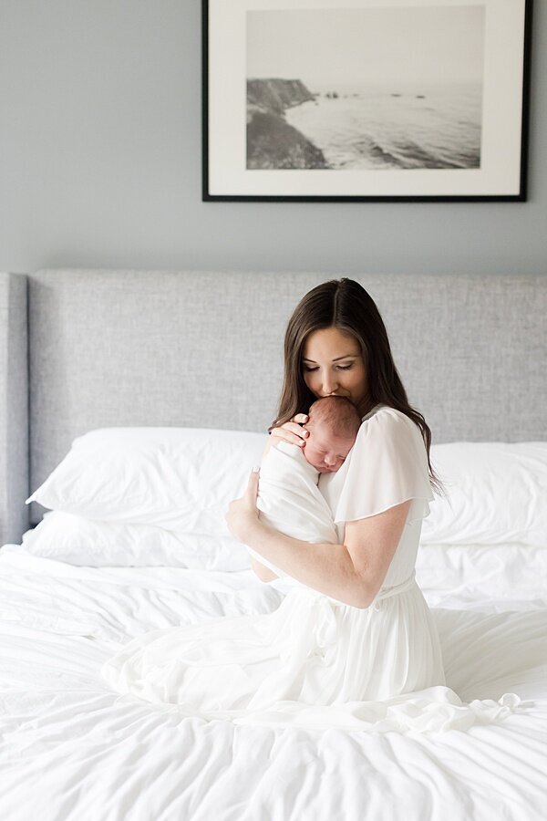 Mom snuggling baby on bed by DC Newborn Photographer Emily