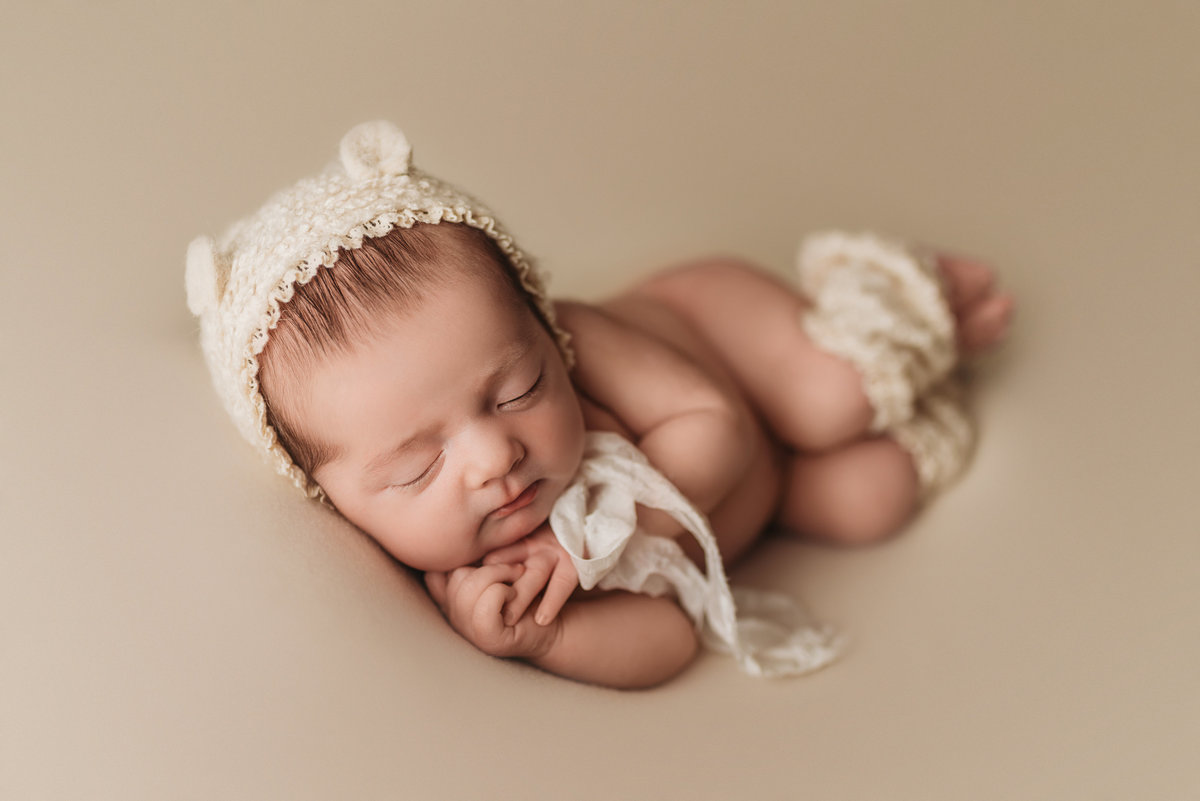 newborn baby wearing beat bonnet posed in Tampa Bay studio