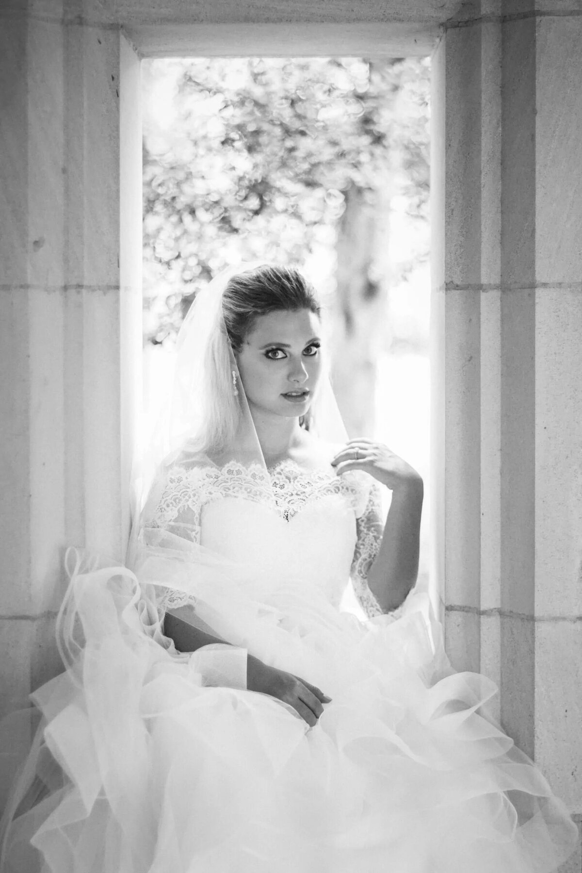 A bride sitting in a small nook with one hand on her shoulder