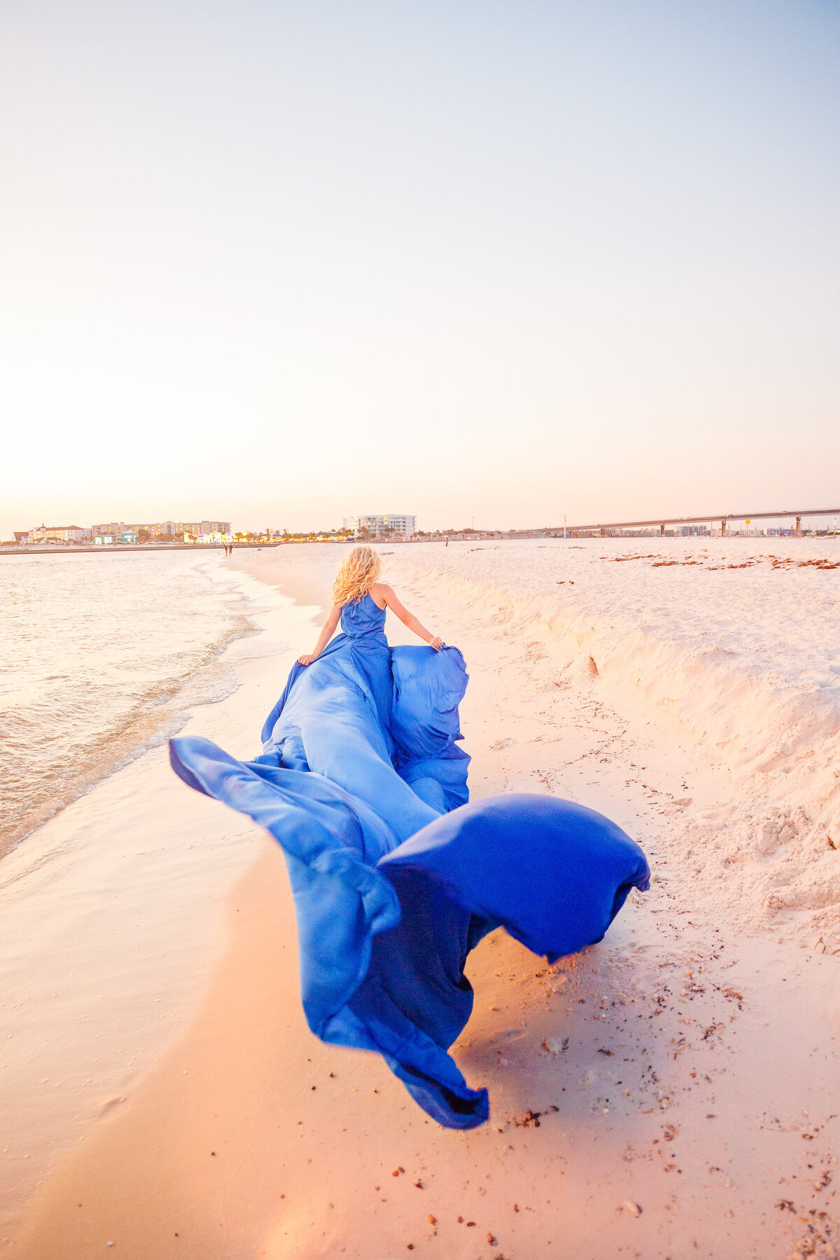 Girl runs along the beaches of Orange Beach, Alabama with a flying dress flowing in the wind behind her.