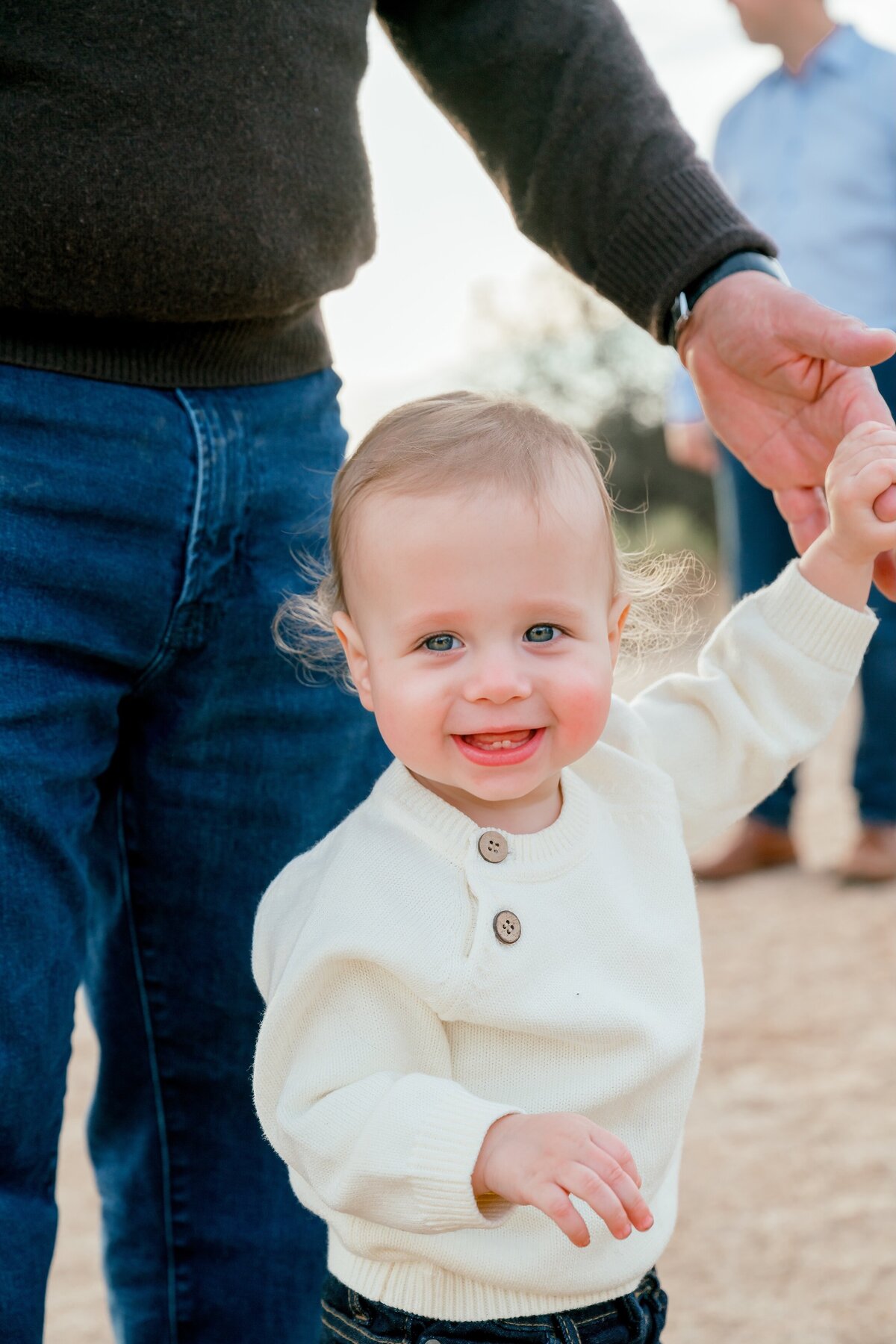 little boy holding grandpa's hand smiling at the camera 