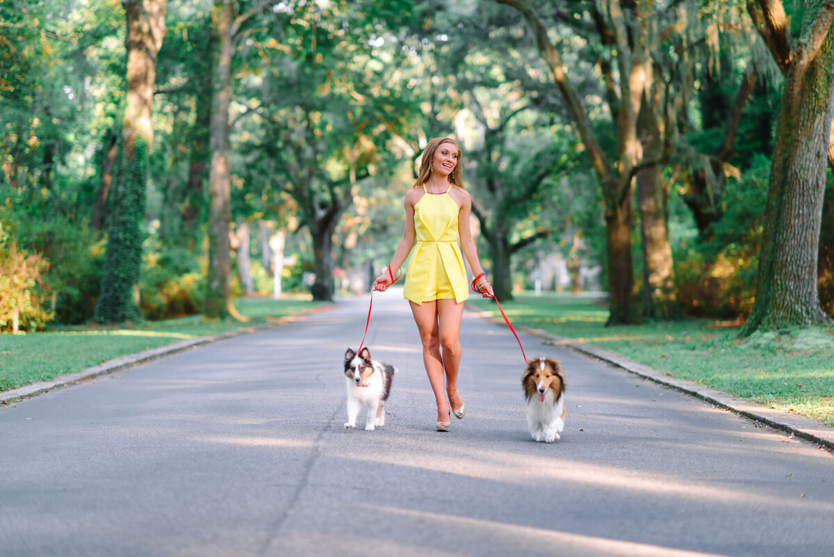 Teen girl walking her dog in yellow dress on historic street in downtown Charleston