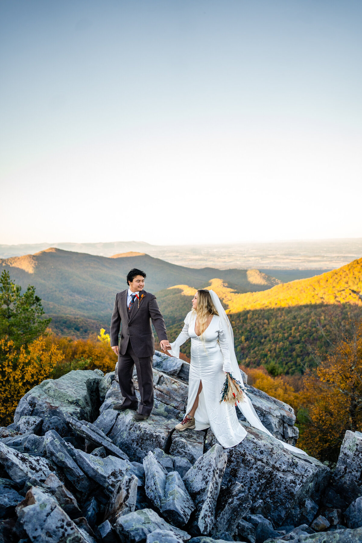 Couple walking across rocky terrain during golden hour elopement