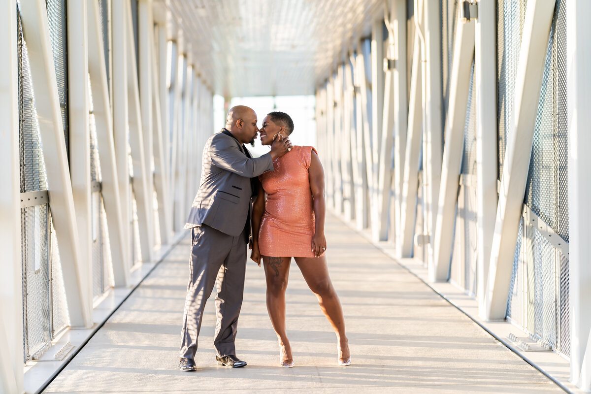 Wedding anniversary photoshoot couple on bridge man wearing grey suit, woman wearing coral sequin dress