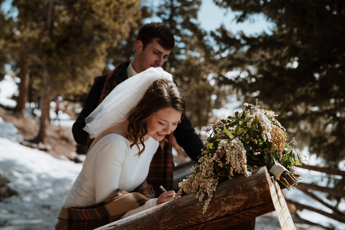 Bride signs marriage license at snowy Sapphire Point elopement in Breckenridge.