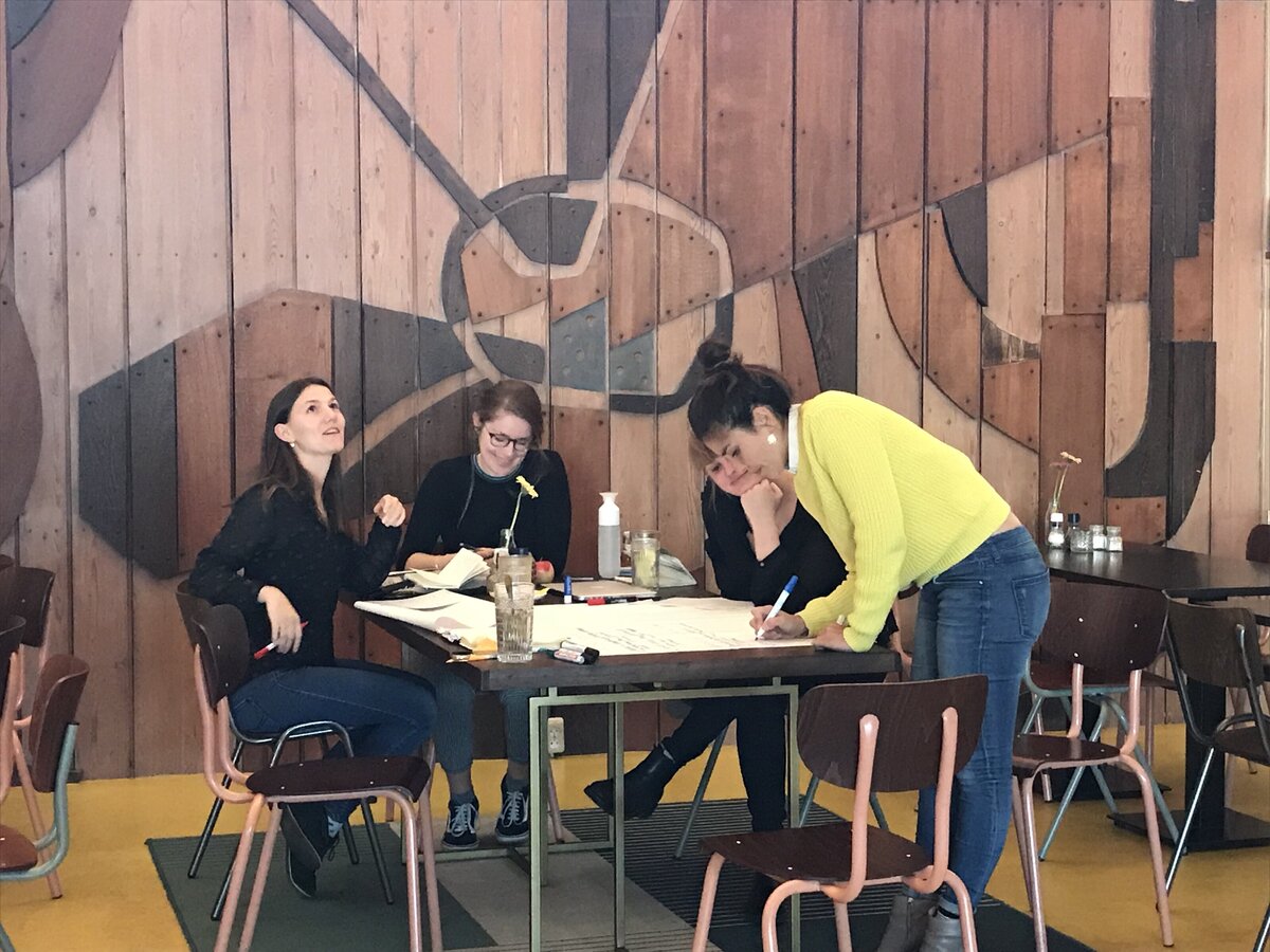 A dynamic business meeting in a creative environment, illustrating Ilse Vonk’s role as a CEO for Yoni.