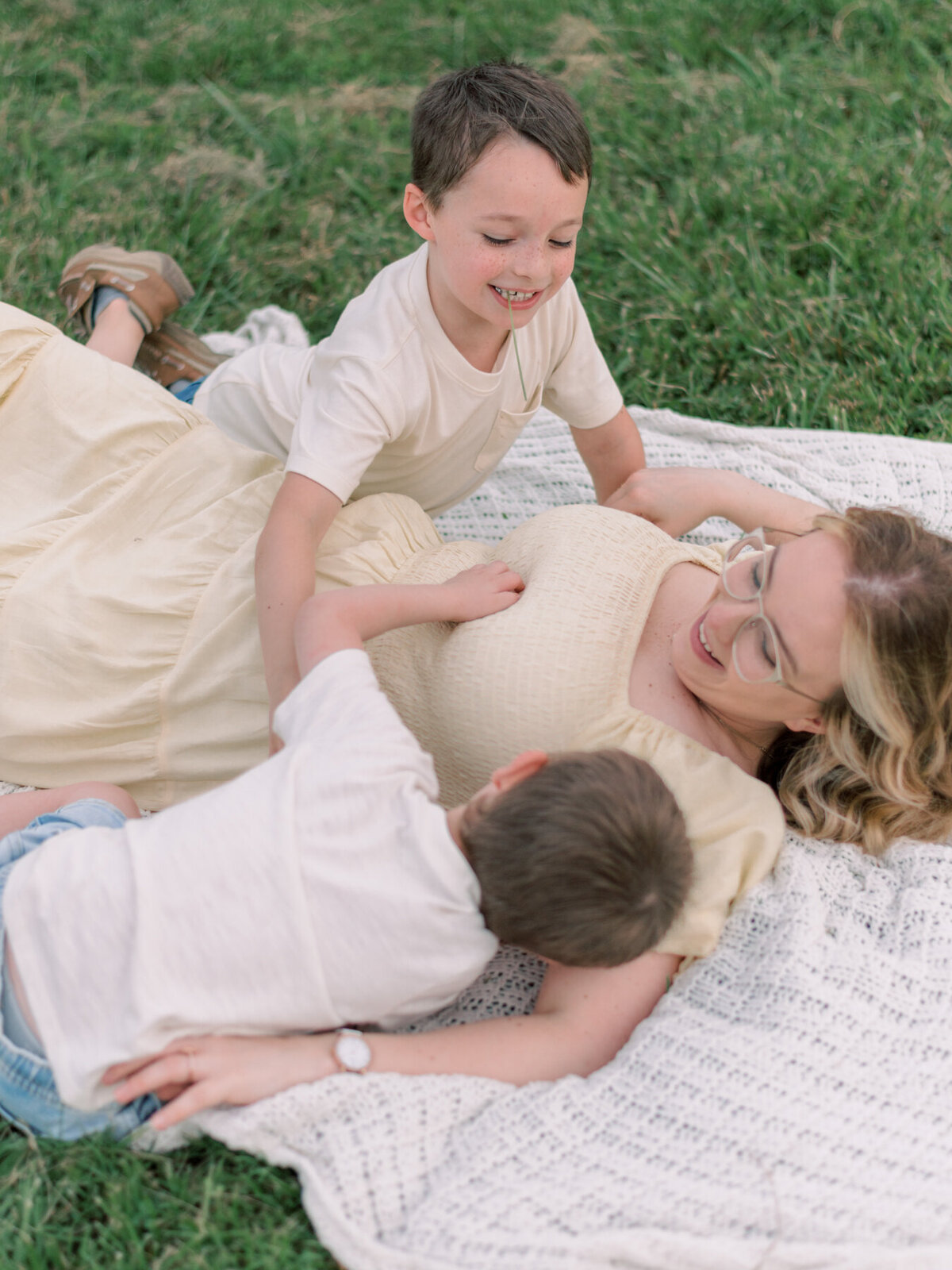 Mom in yellow dress laying on blanket with her two young boys in Richdmond.