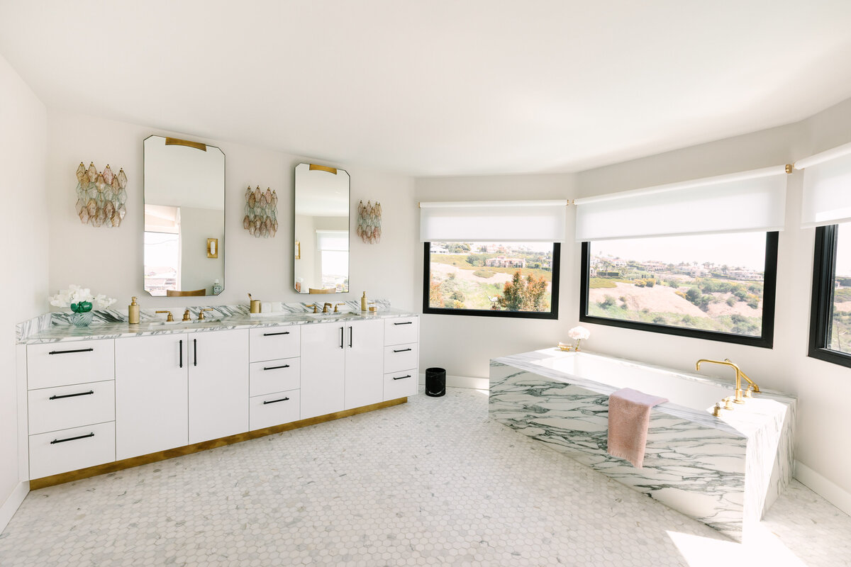 Primary bathroom with white high gloss vanity and brass base, Arabescato Corchia marble counters, vintage Carlo Scarpa Venini sconces, and freestanding marble tub.